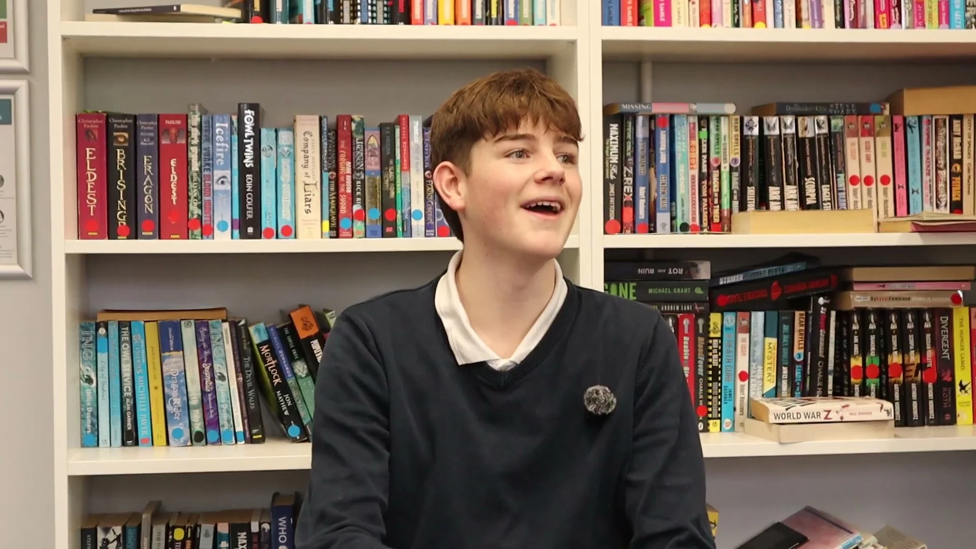 A smiling pupil talking in a school library